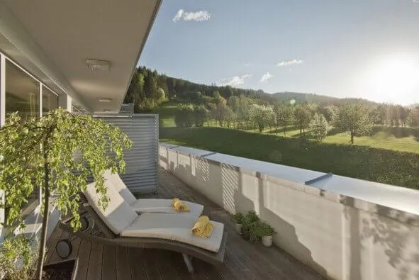Balkonblick über Wiese und Waldlandschaft im grünen Tal