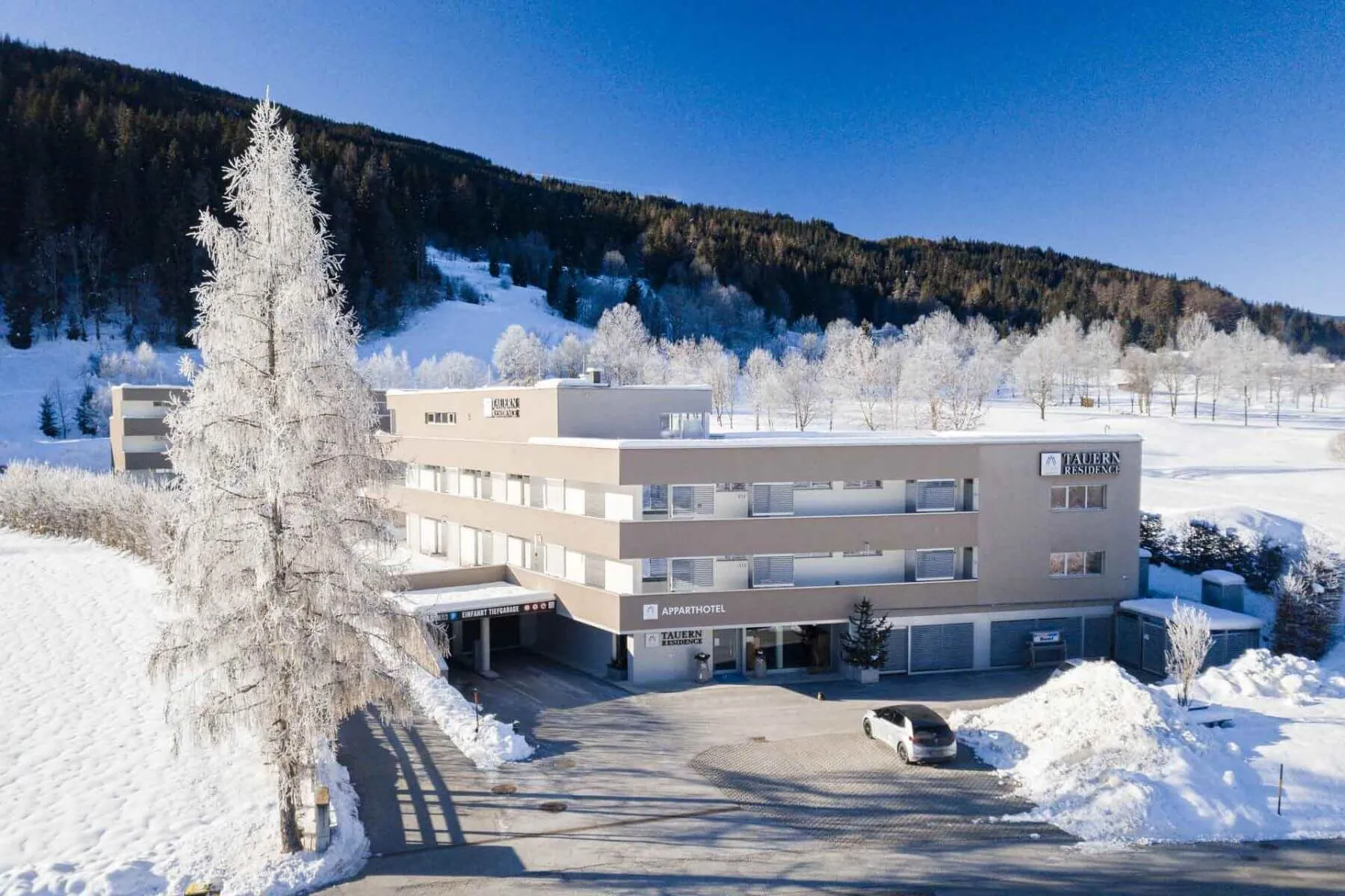 Aparthotel-Gebäude in Schneetallandschaft mit Raureif-Bäumen
