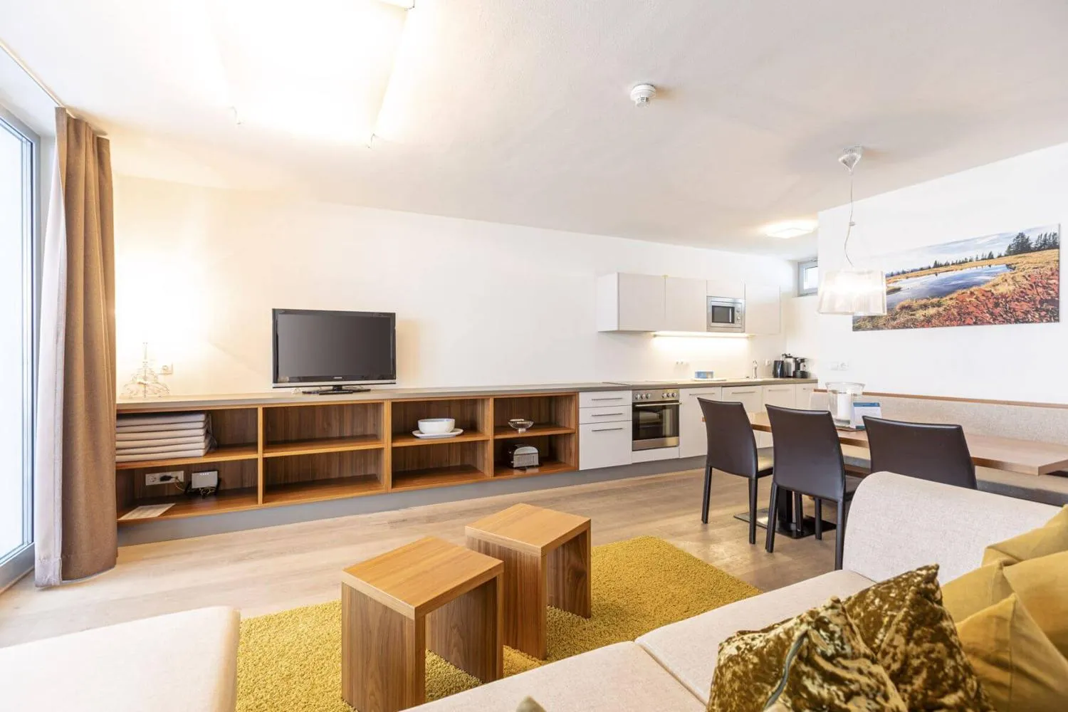Offene Wohnküche mit Sofas, Holzmöbeln und großer Fensterfront