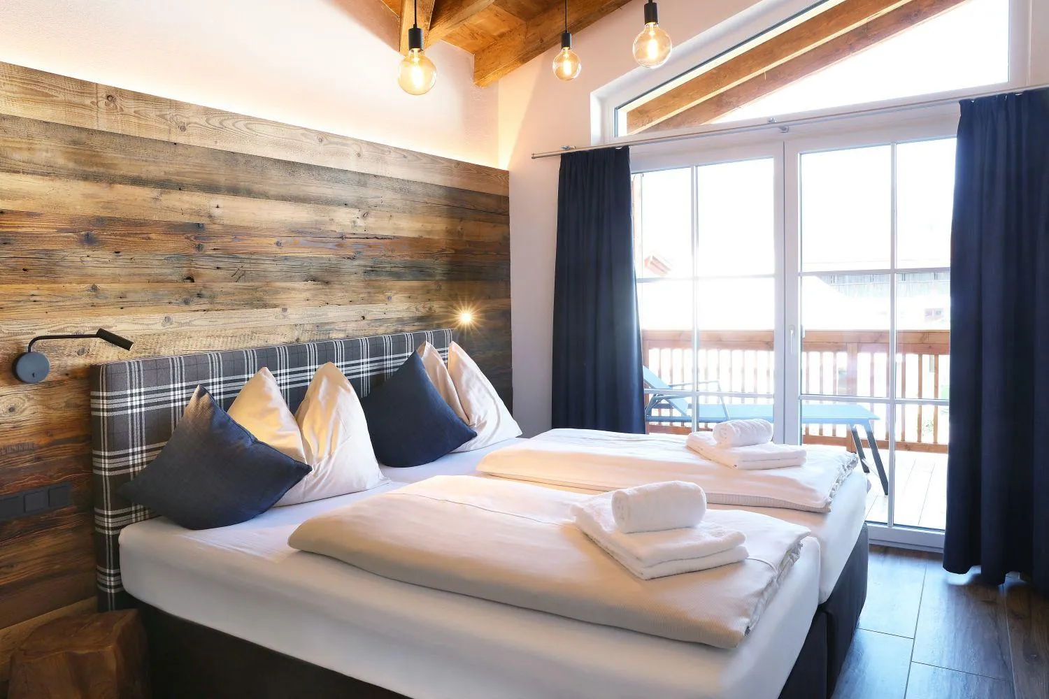 Schlafzimmer mit Holzwand-Kopfteil, Balkonzugang und kariertem Kissen