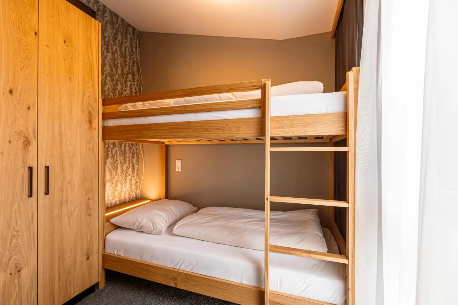 Kinderzimmer mit zwei Etagenbetten aus Holz und Kleiderschrank
