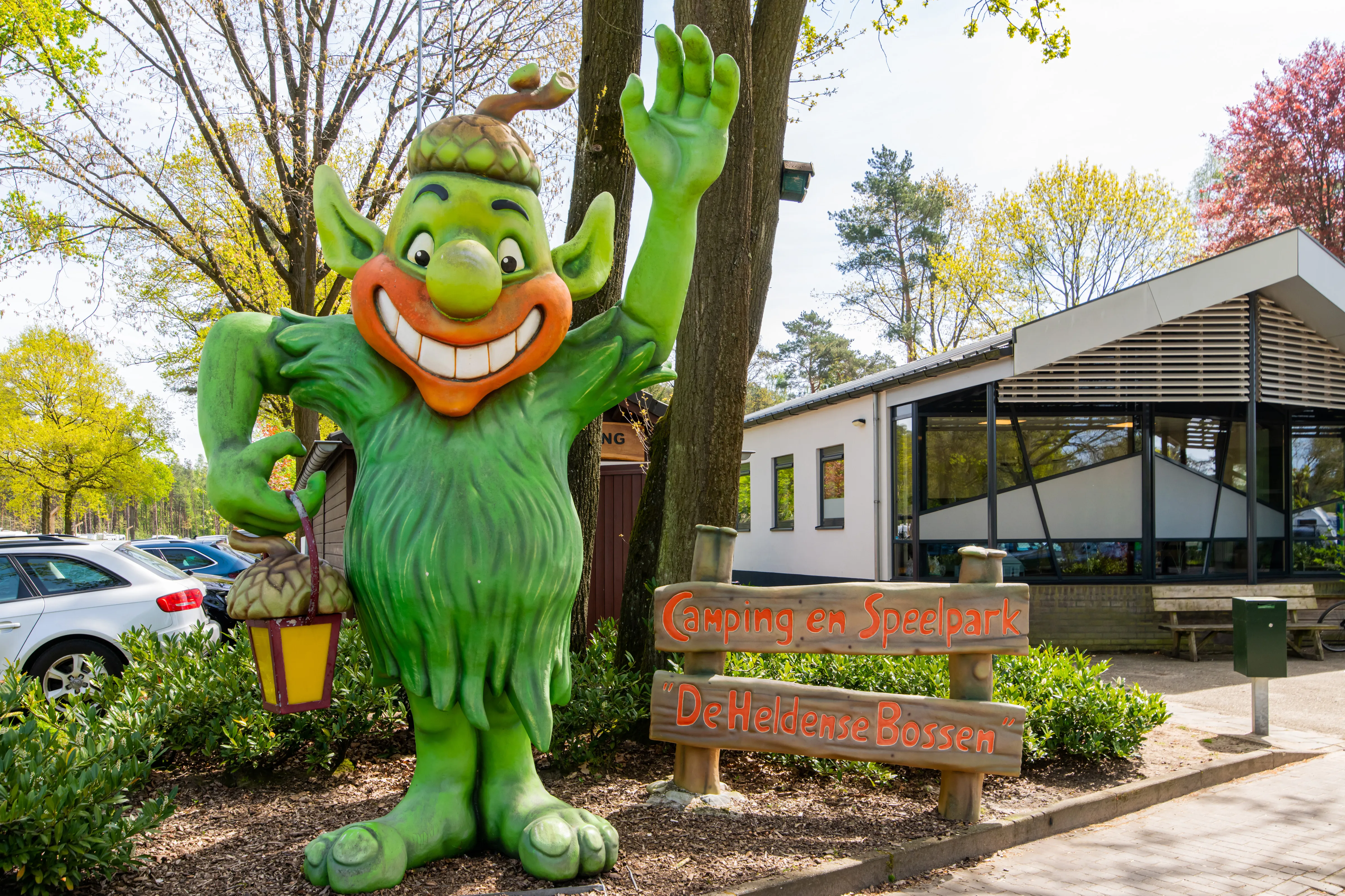 Grüne Waldschrat-Figur mit Laterne vor dem Rezeptionsgebäude am Parkeingang