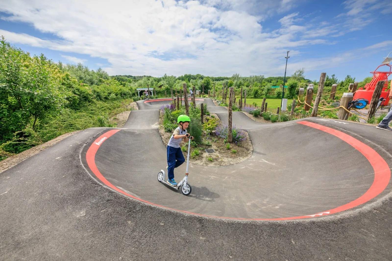 Pumptrack der Outdoor-Funzone mit Kind auf dem Roller