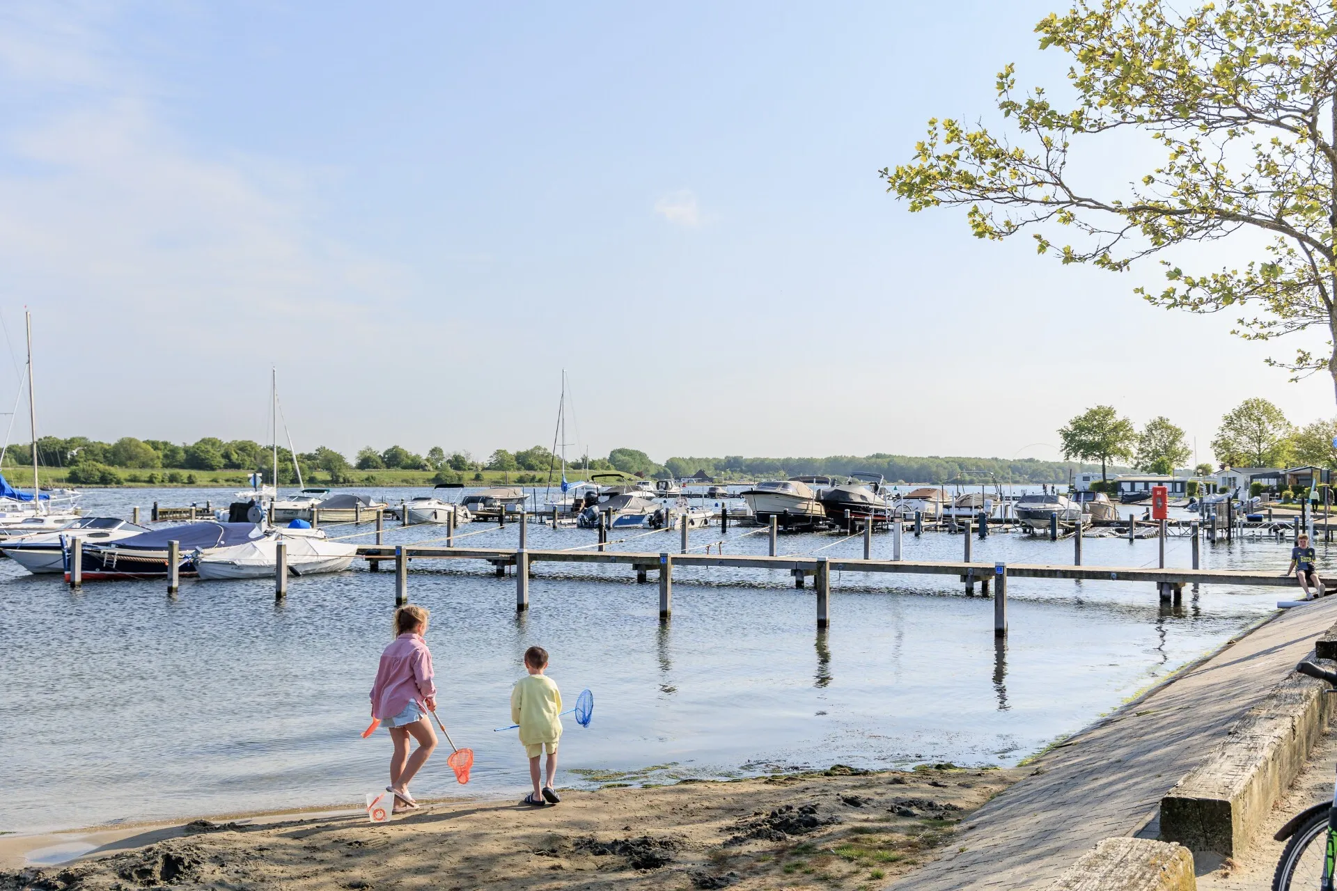 Bootsstege mit Segel- und Motorbooten im Veerse Meer, davor Kinder mit Keschern am Sandufer