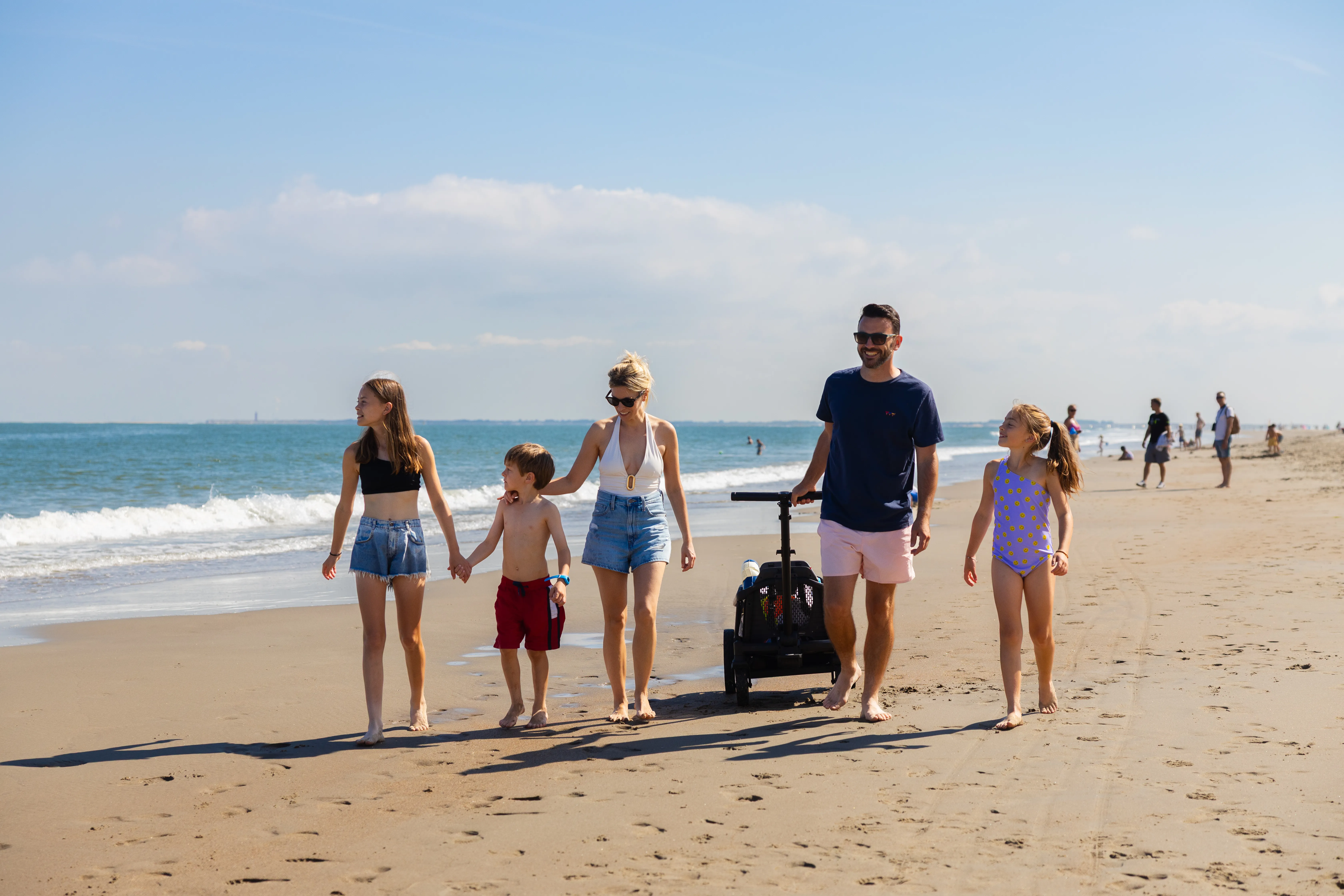 Familie mit Bollerwagen am Nordseestrand bei ablaufendem Wasser