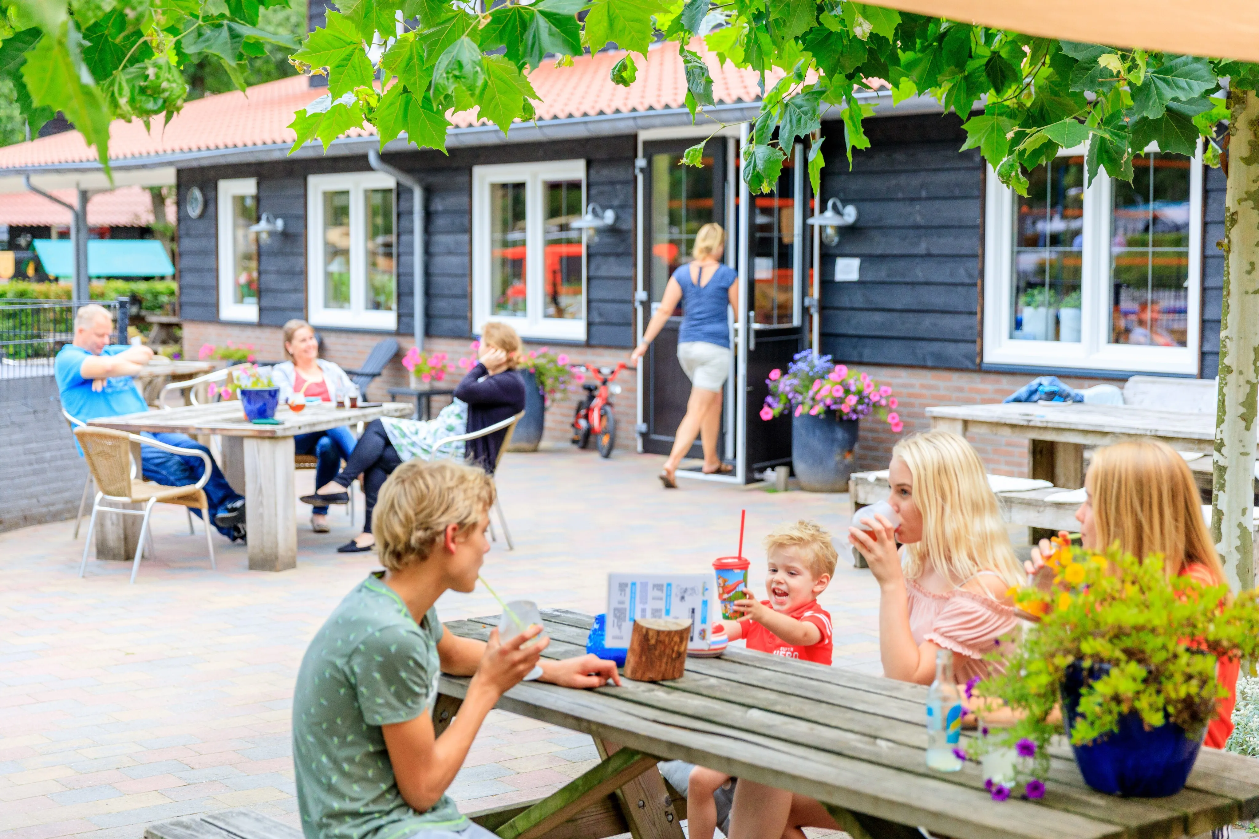 Terrasse von Heggies mit Gästen an Picknicktischen vor dem dunklen Holzgebäude