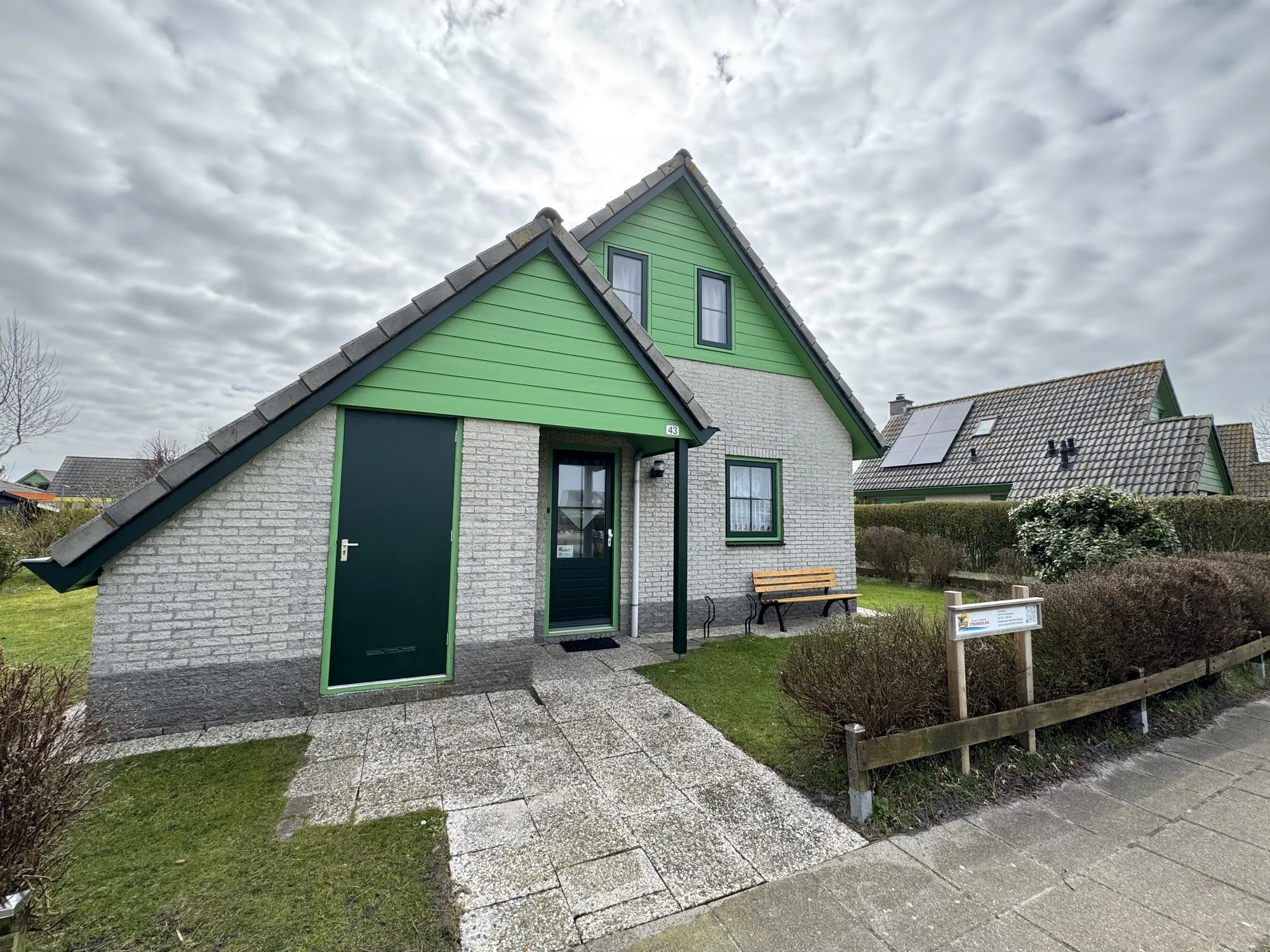 Eingangsseite eines Bungalows mit Abstellraum und Sitzbank