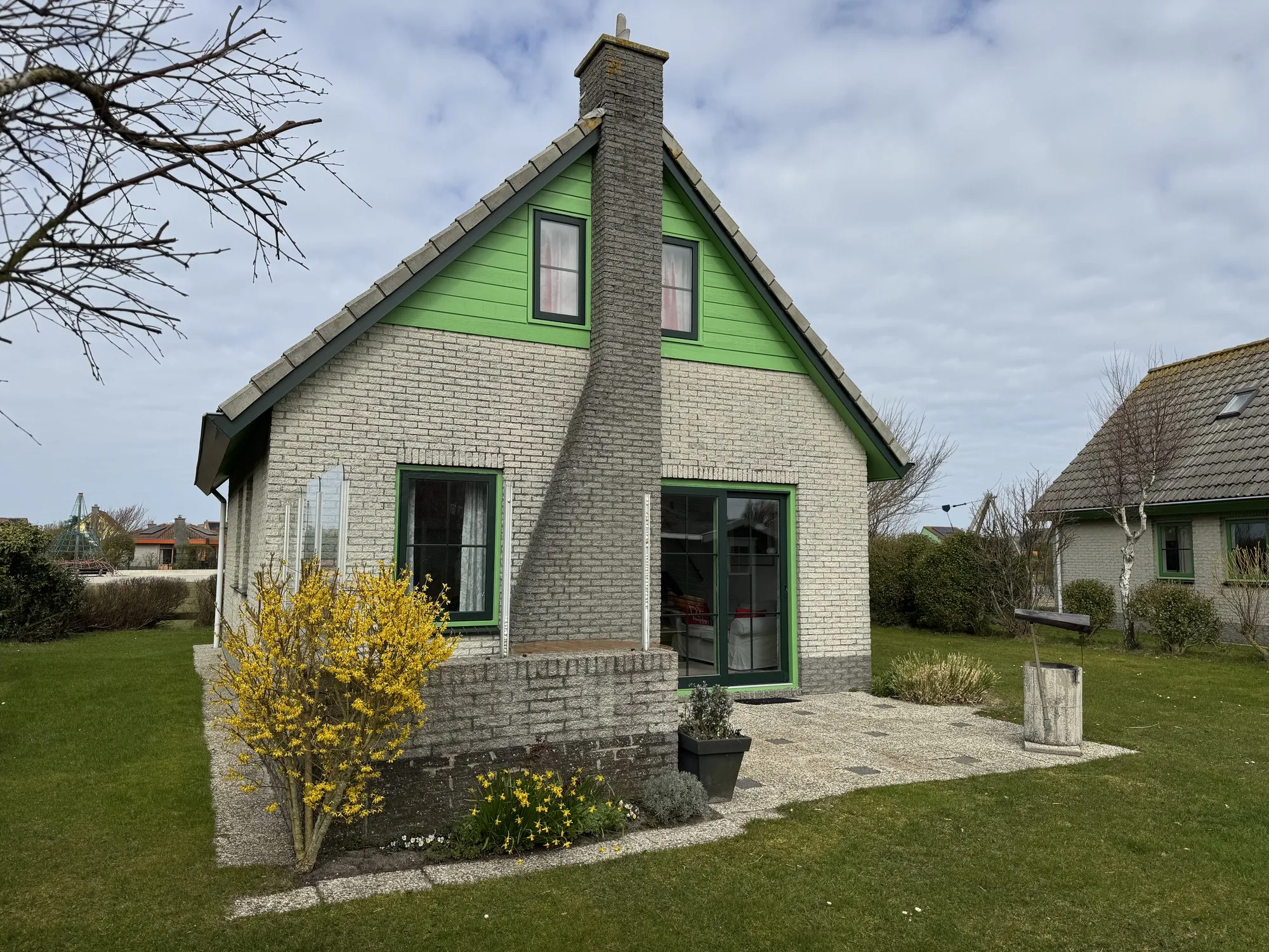 Giebelseite eines Bungalows mit Kamin und Terrasse