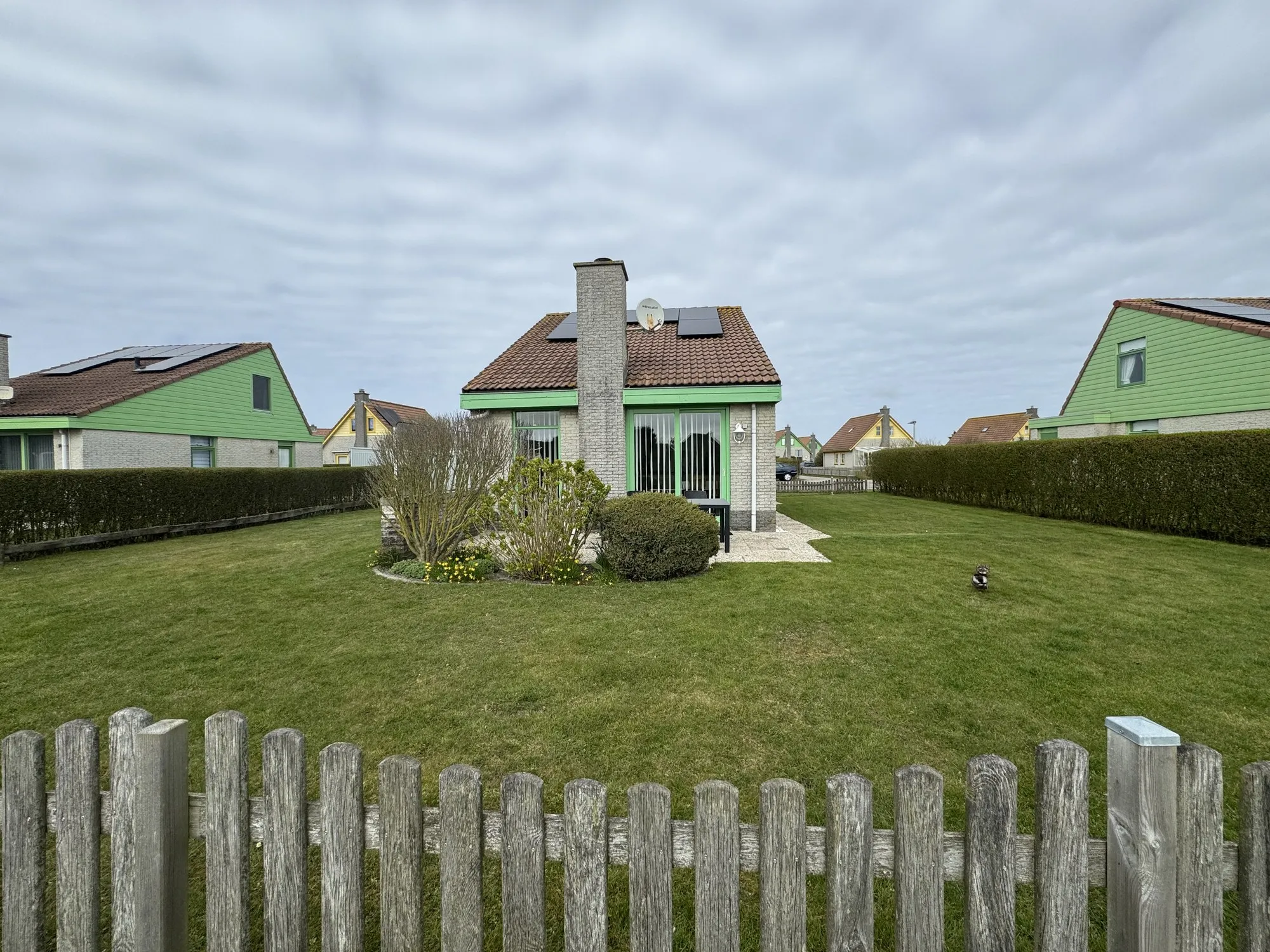Bungalow hinter Holzzaun mit weitem Rasengrundstück