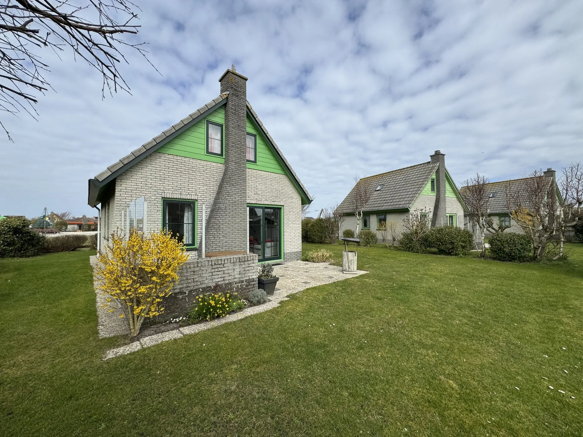 Bungalow mit Terrasse und blühender Forsythie im Vorgarten