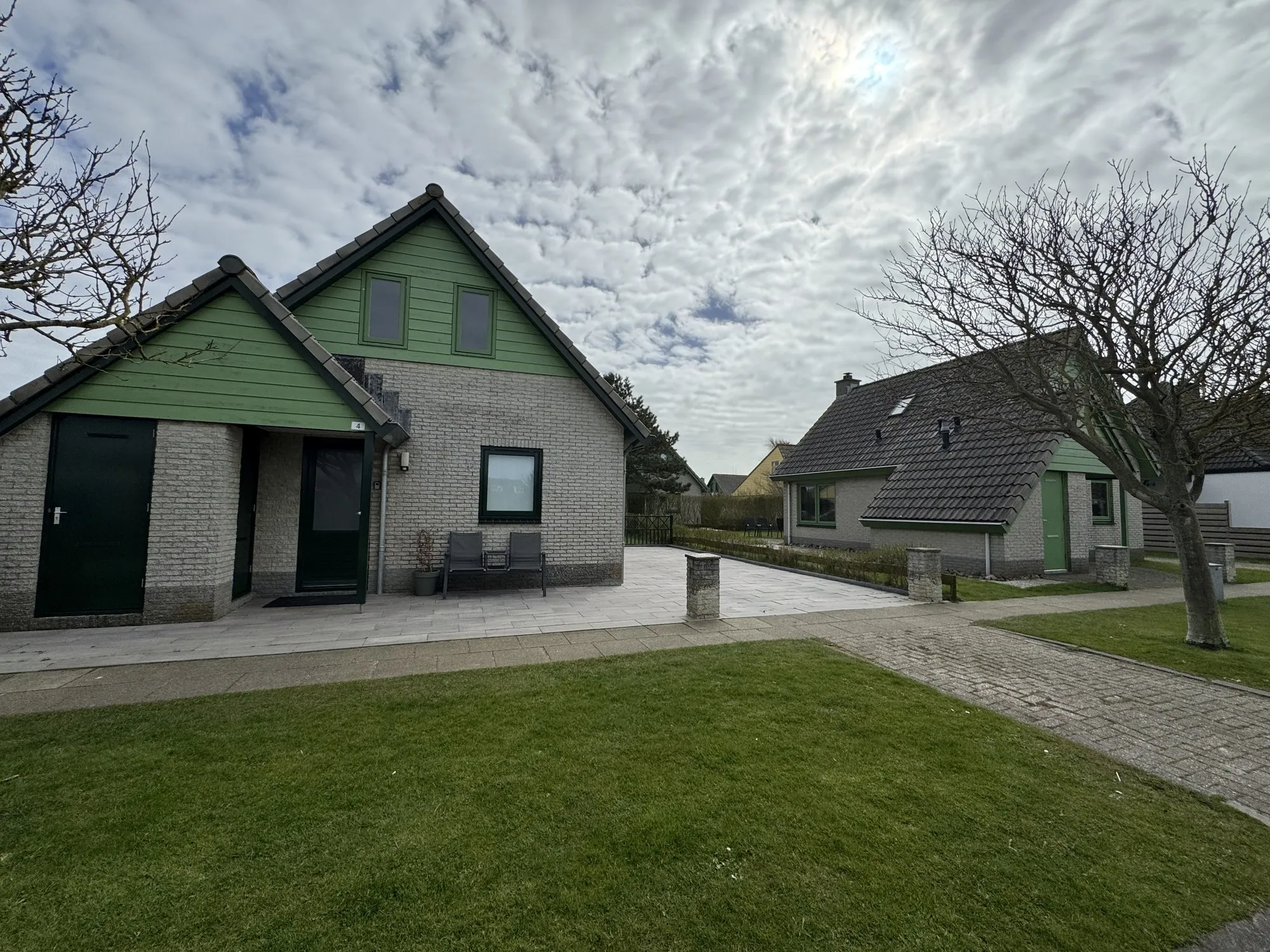 Zwei Bungalows mit gepflasterter Terrasse und Rasenfläche
