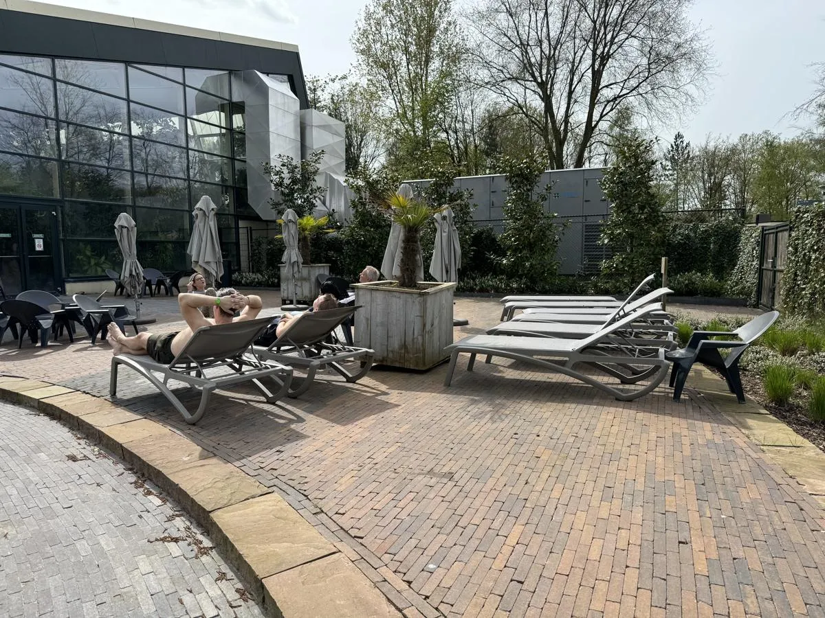 Außenbereich mit Liegestühlen und Sonnenschirmen vor der Hallenbadanlage