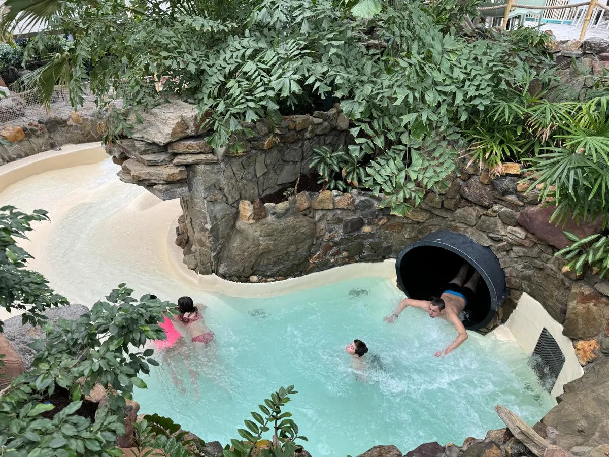 Wildwasserbahn in tropischem Becken, umgeben von Felsen und grüner Vegetation
