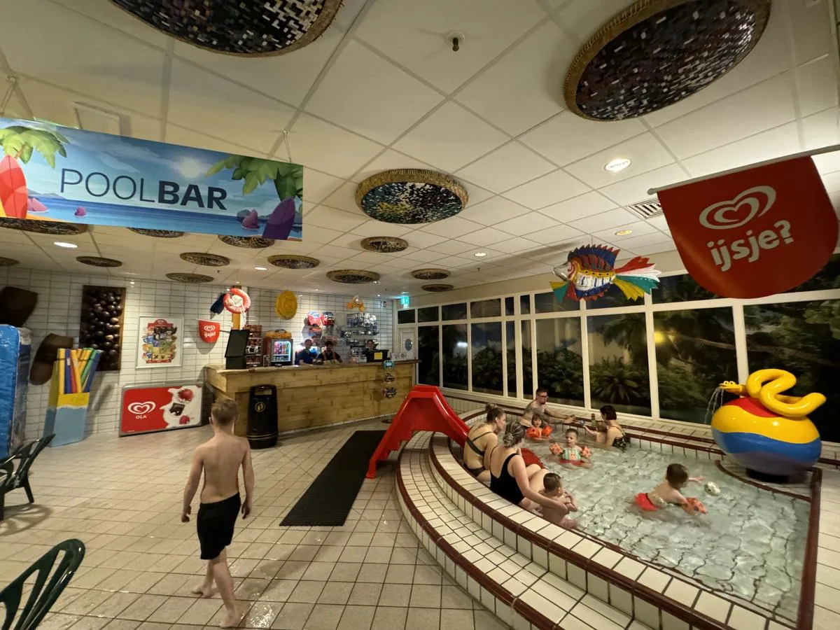 Hallenbad-Planschbecken mit roter Rutsche und spielenden Kindern