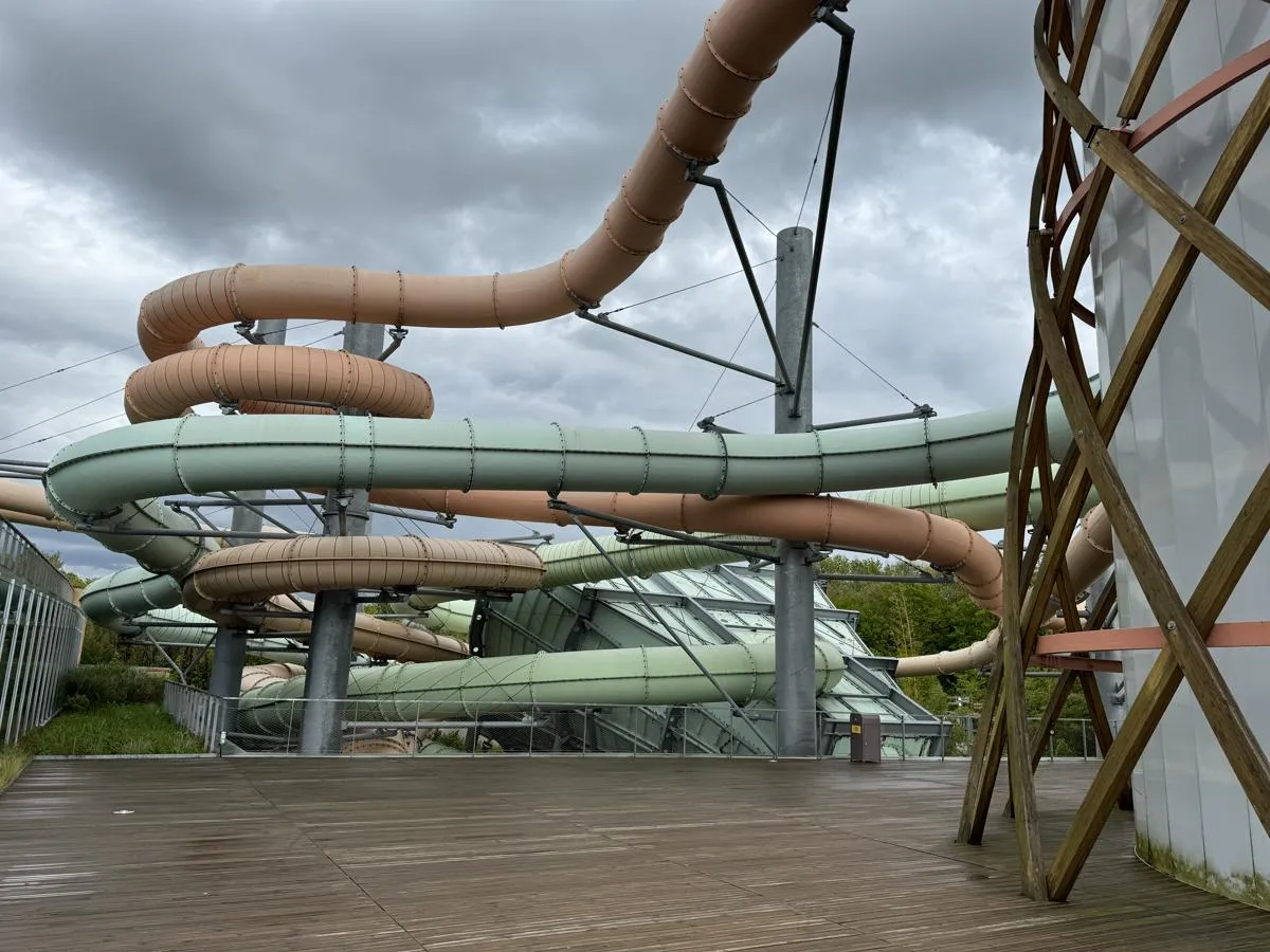 Mehrere große Kunststoffrutschen in Beige und Grün auf Stahlträgern