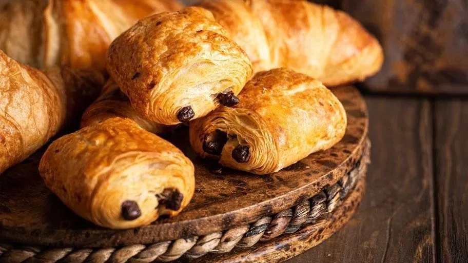 Goldbraune Schokocroissants auf rustikalem Holzbrett in Nahaufnahme fotografiert