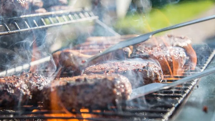 Fleischstücke grillen auf dem Grill mit Flammen und Qualm