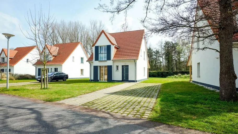 Straßenansicht von Feriendorf mit weißen Häusern, orangeroten Dächern und gepflasterter Zufahrt