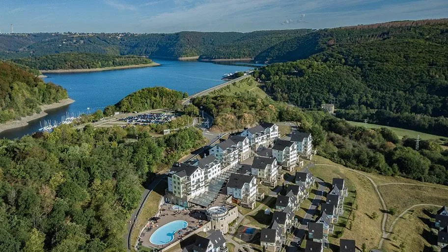 Ferienpark aus der Luft mit großem Stausee und bewaldeter Eifellandschaft
