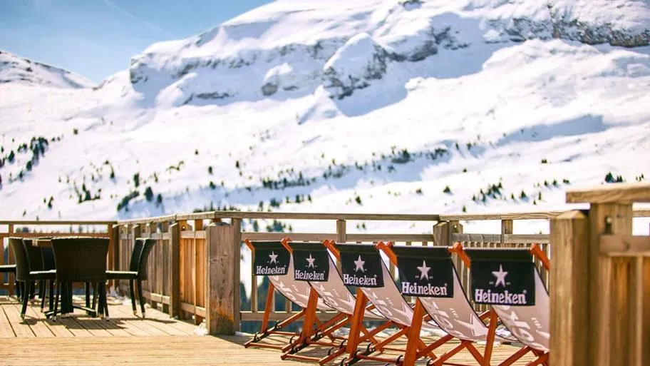 Außenterrasse mit Liegestühlen und schneebedecktem Bergpanorama im Hintergrund