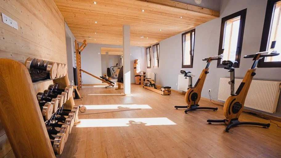 Fitnessraum mit Hanteln, Trainingsgeräten und Holzdecke, Fensterausblick