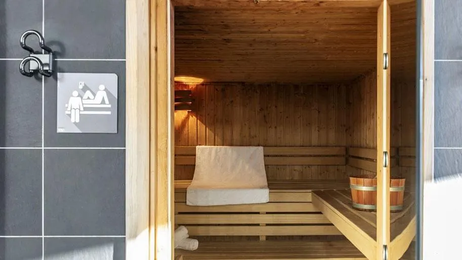 Geöffnete Saunatür mit Holzinnenraum und Piktogramm für Frauensauna