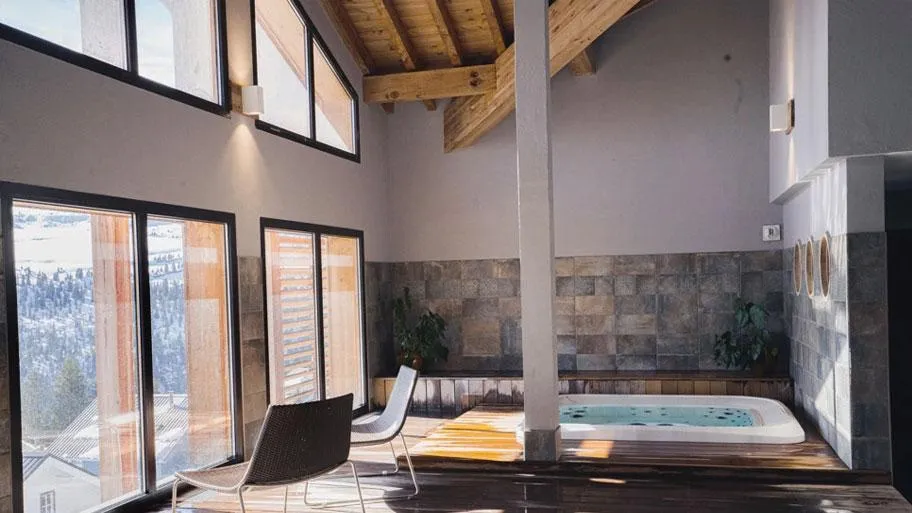 Wellnessraum mit Whirlpool, großer Fensterfront und Holzdecke