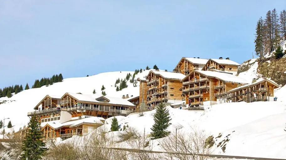 Bergresort mit Holzgebäuden im Schnee vor alpiner Berglandschaft