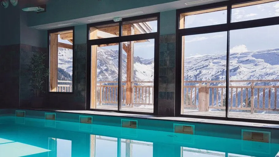 Hallenbad mit Fensterfront in Türkis und Bergblick durch Glasflächen