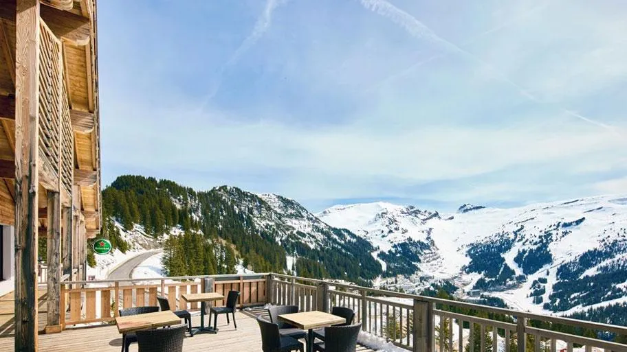 Holzterrasse mit Sitzmöbeln und Panoramablick auf verschneite Berggipfel
