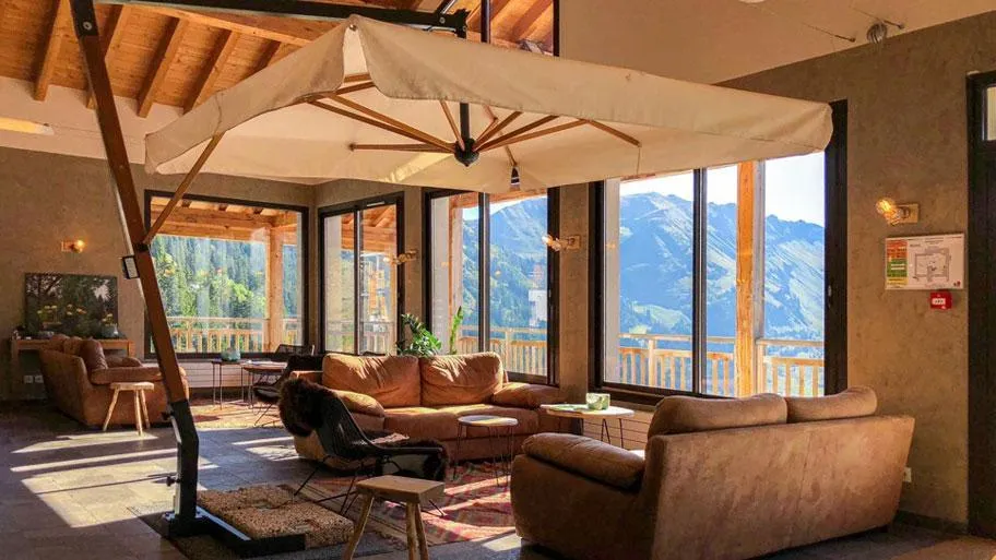 Wohnzimmer mit braunem Ledersofa und großem Fenster mit Bergblick