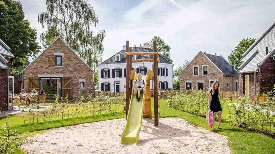 Rutschspielplatz vor modernen Häusern in grüner Umgebung