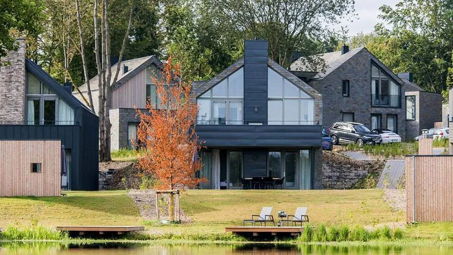 Dunkles Ferienhaus am Wasser mit Bootssteg und Wiese