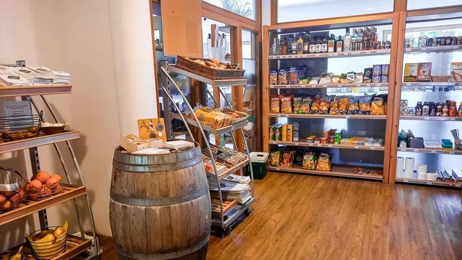 Hofladen mit Holzfass, Brot und Regalen mit regionalen Produkten