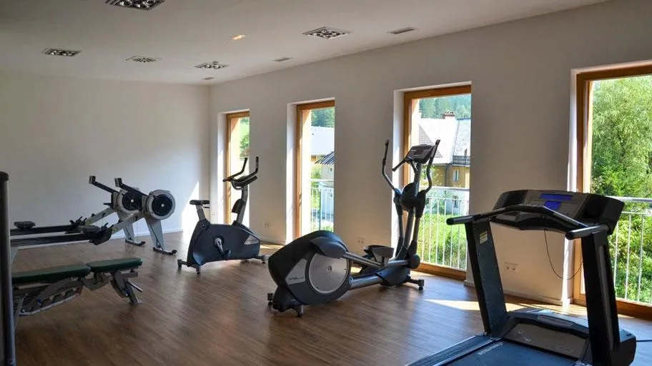 Fitnessstudio mit Trainingsgeräten und großen Fenstern mit Ausblick