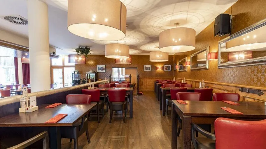 Modernes Restaurant mit roten Stühlen, Holztischen und Designerleuchten