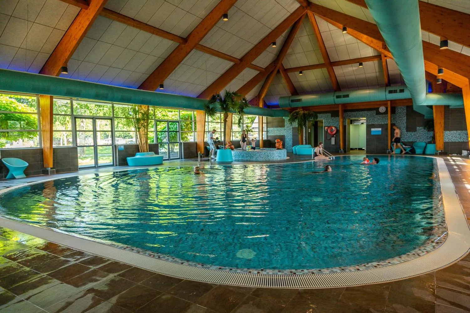 Schwimmbecken im Hallenbad mit Holzdachkonstruktion und großen Fenstern