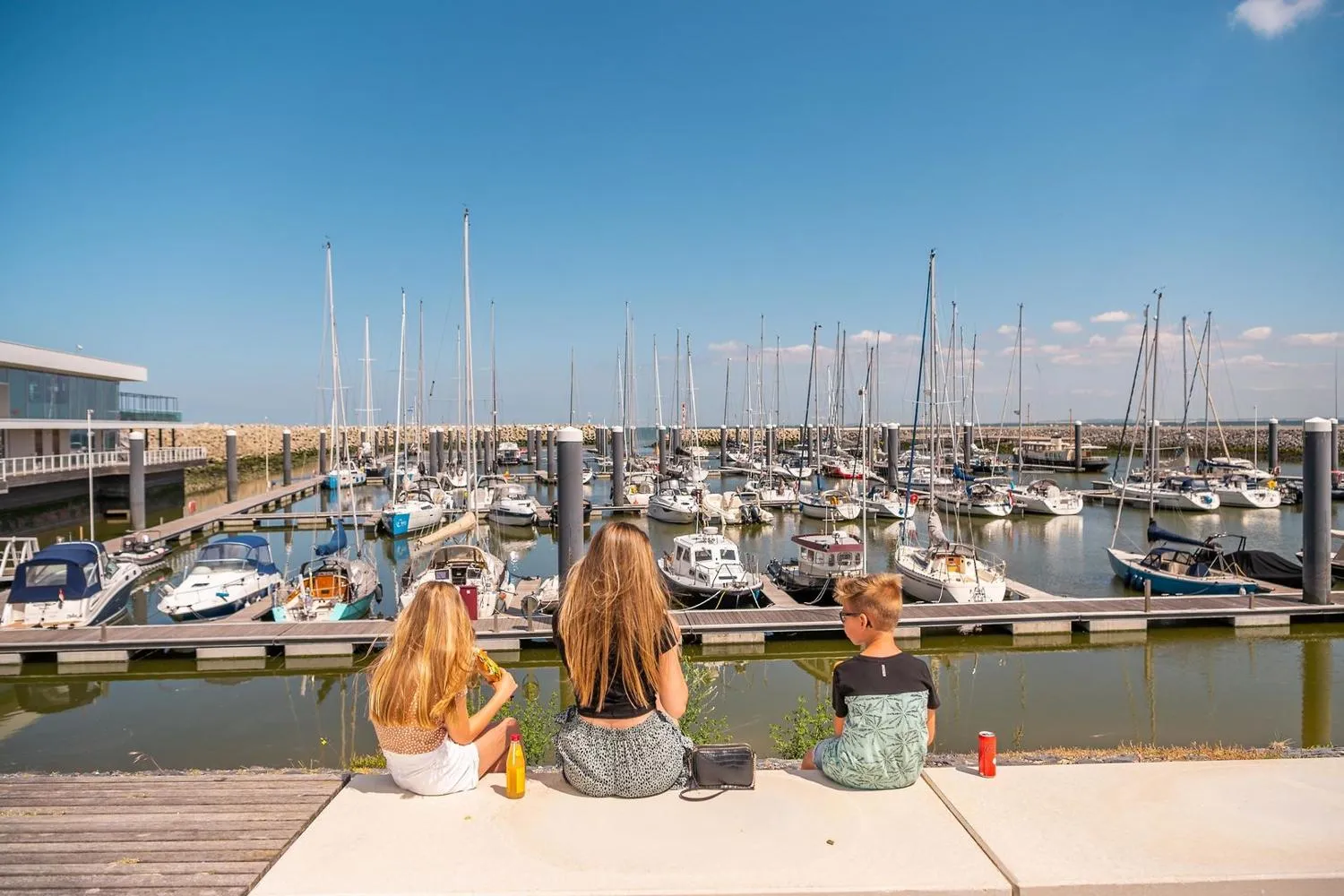 Drei Personen blicken auf Segelboothafen mit Masten