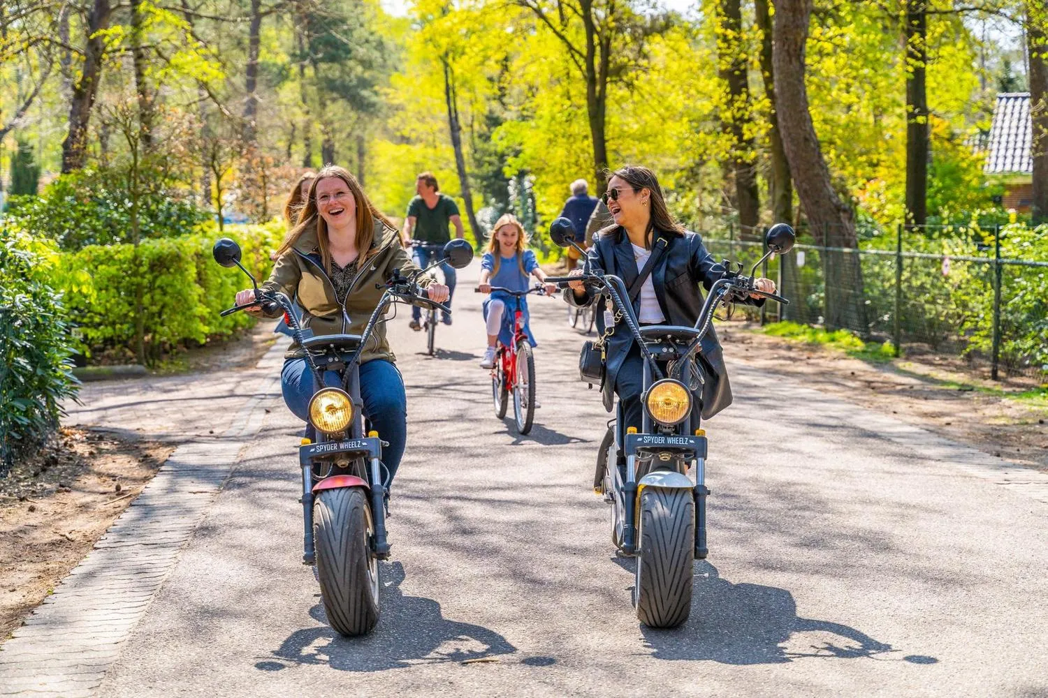 Besucherinnen fahren auf Elektro-Rollern auf Parkwegen