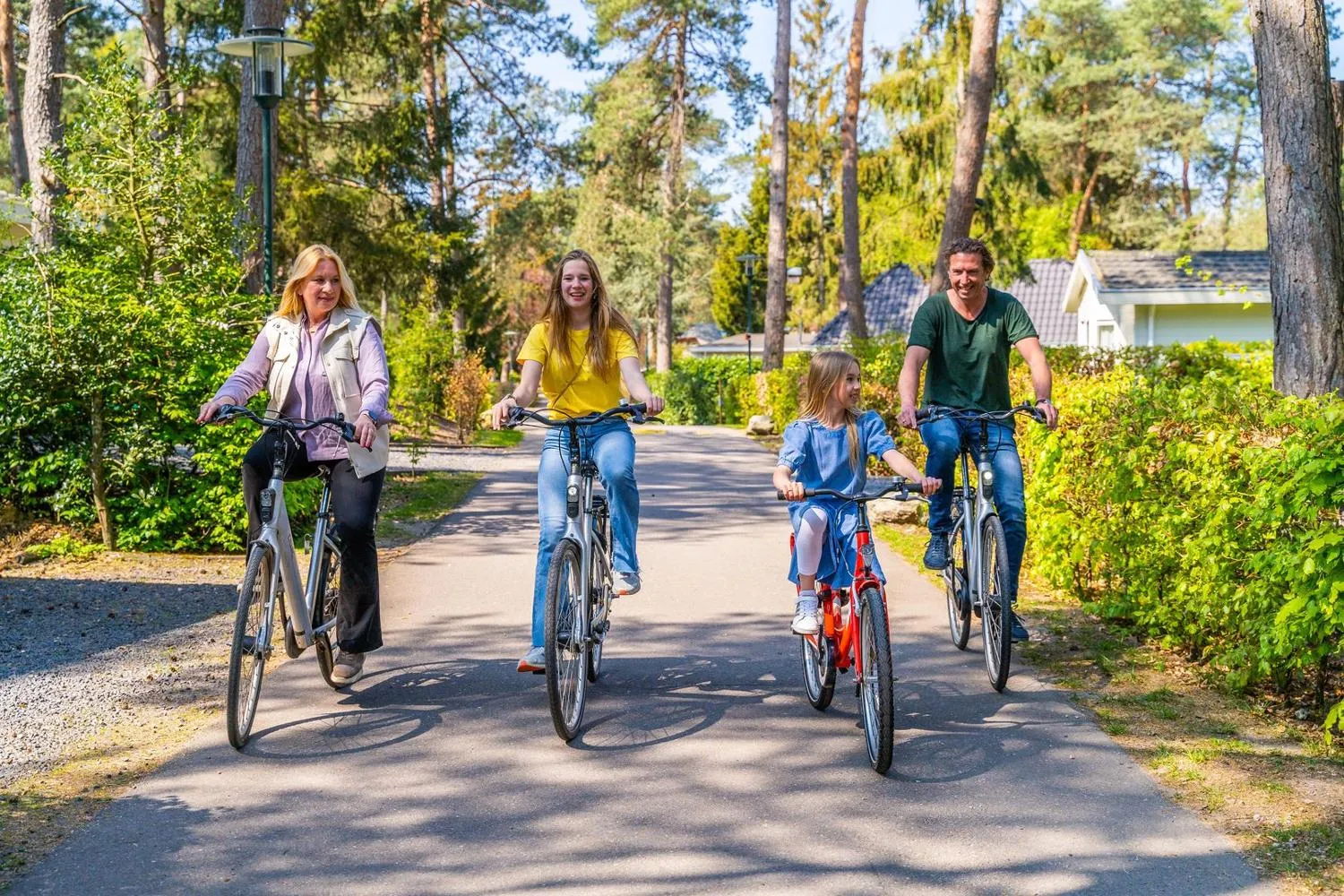 Familie radelt auf gepflegtem Parkweg durch grüne Umgebung
