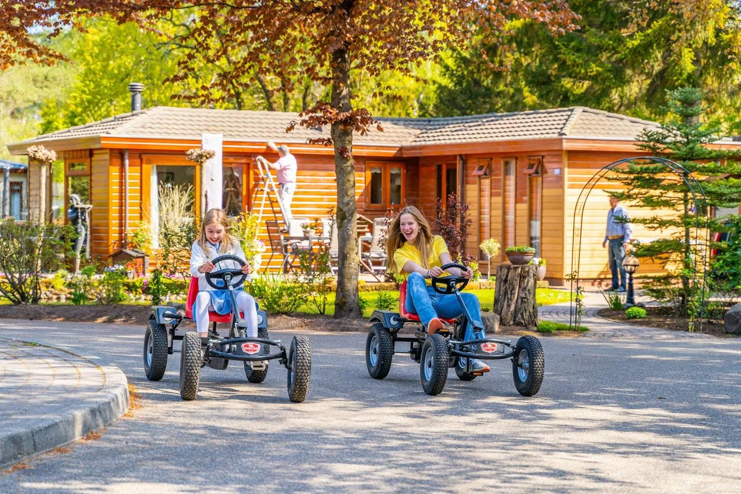Kinder fahren Go-Karts auf Straße vor Holzhäusern