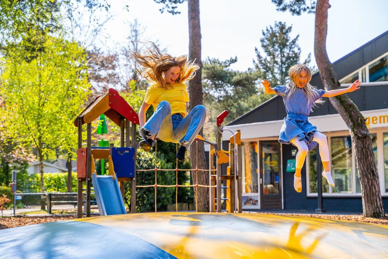 Kinder spielen auf Trampolin bei Freizeitgebäude und Spielplatz