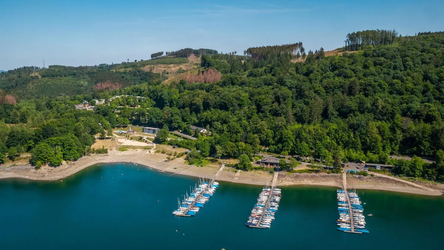Ferienpark neben See mit Anlegestellen und Waldkulisse