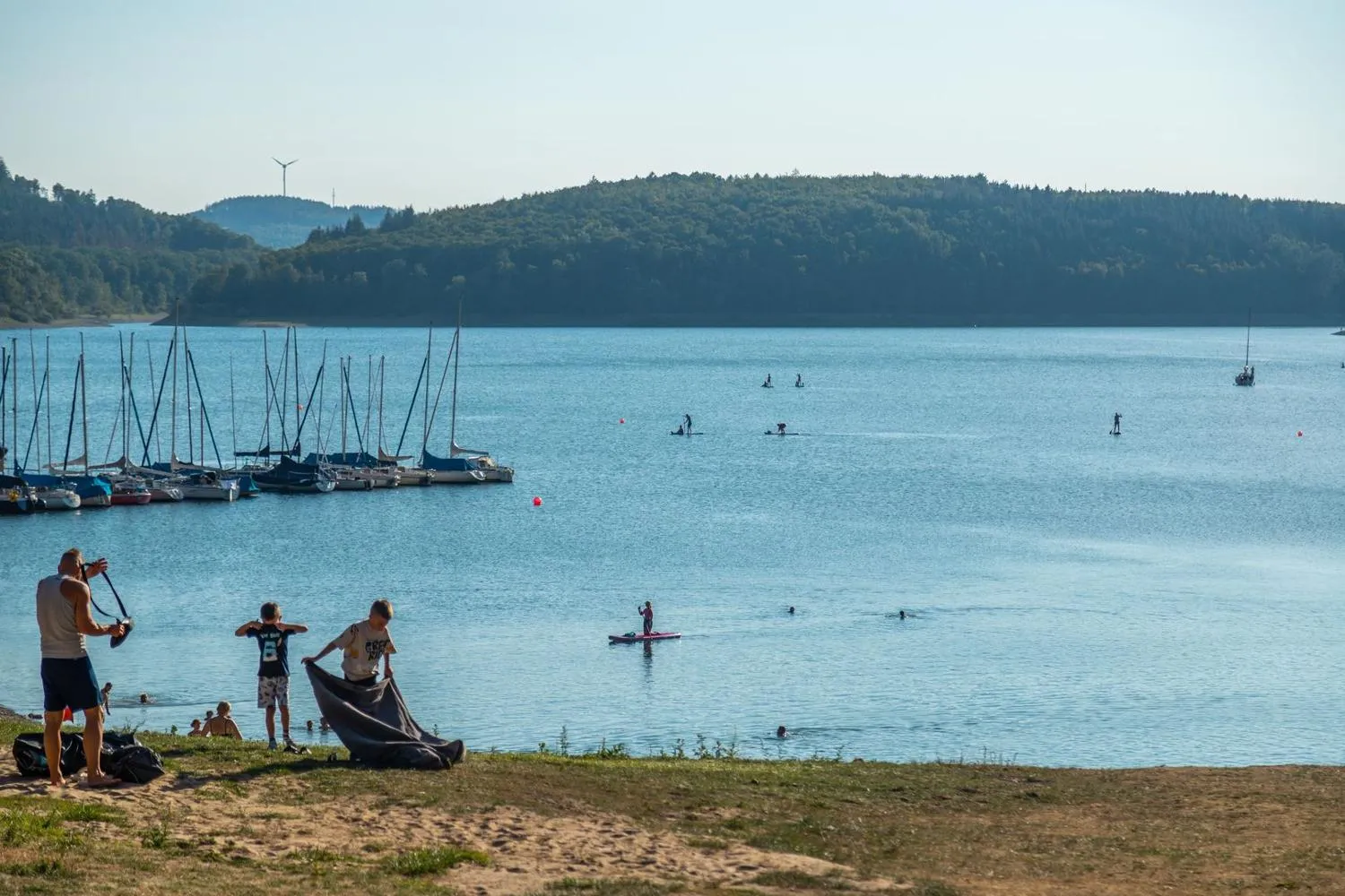 Badestrand mit Schwimmern und Seglern auf Biggesee
