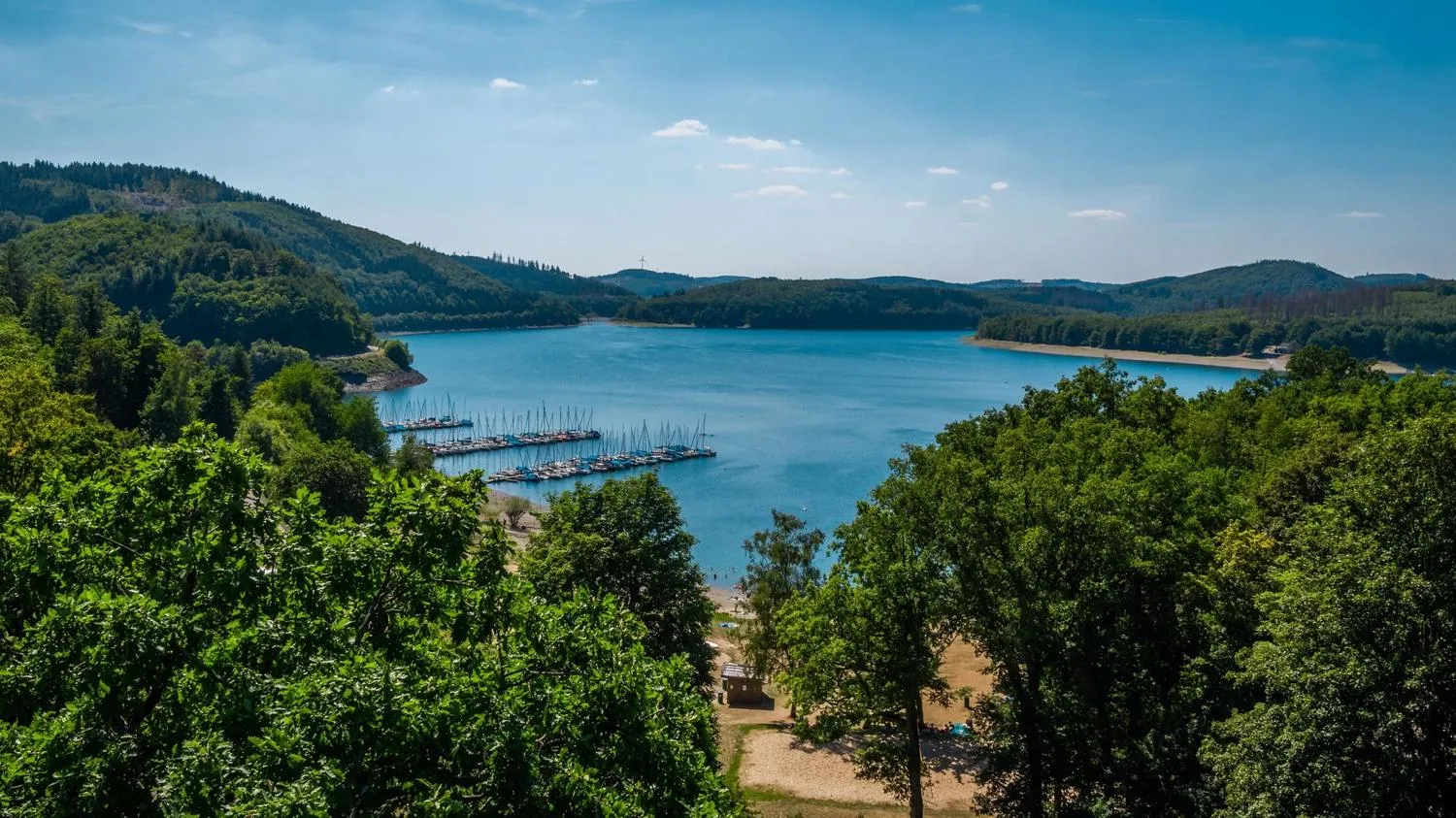 Biggesee mit Bootsanlegestelle, Wäldern und Ferienpark