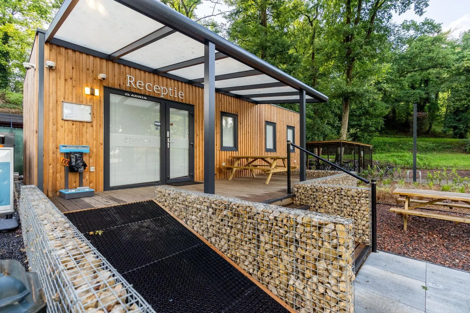 Rezeptionsgebäude aus Holz und Stein mit Pergola-Dach