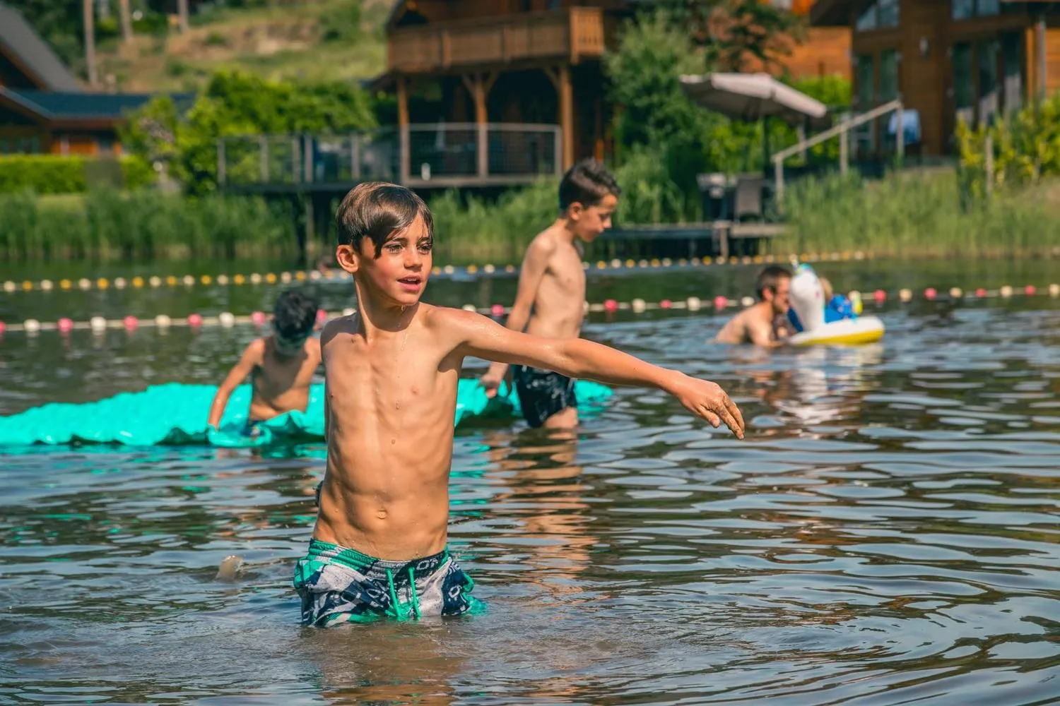 Kinder spielen mit Schwimmaccessoires im flachen Wasser
