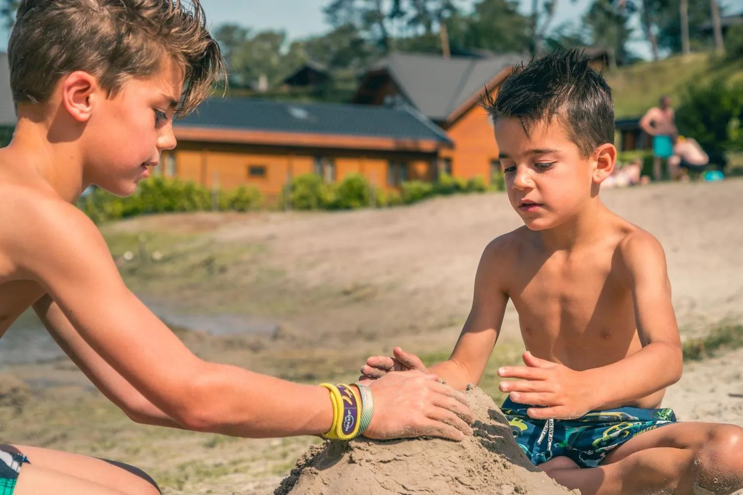 Zwei Jungen spielen und bauen Burgen am Sandstrand