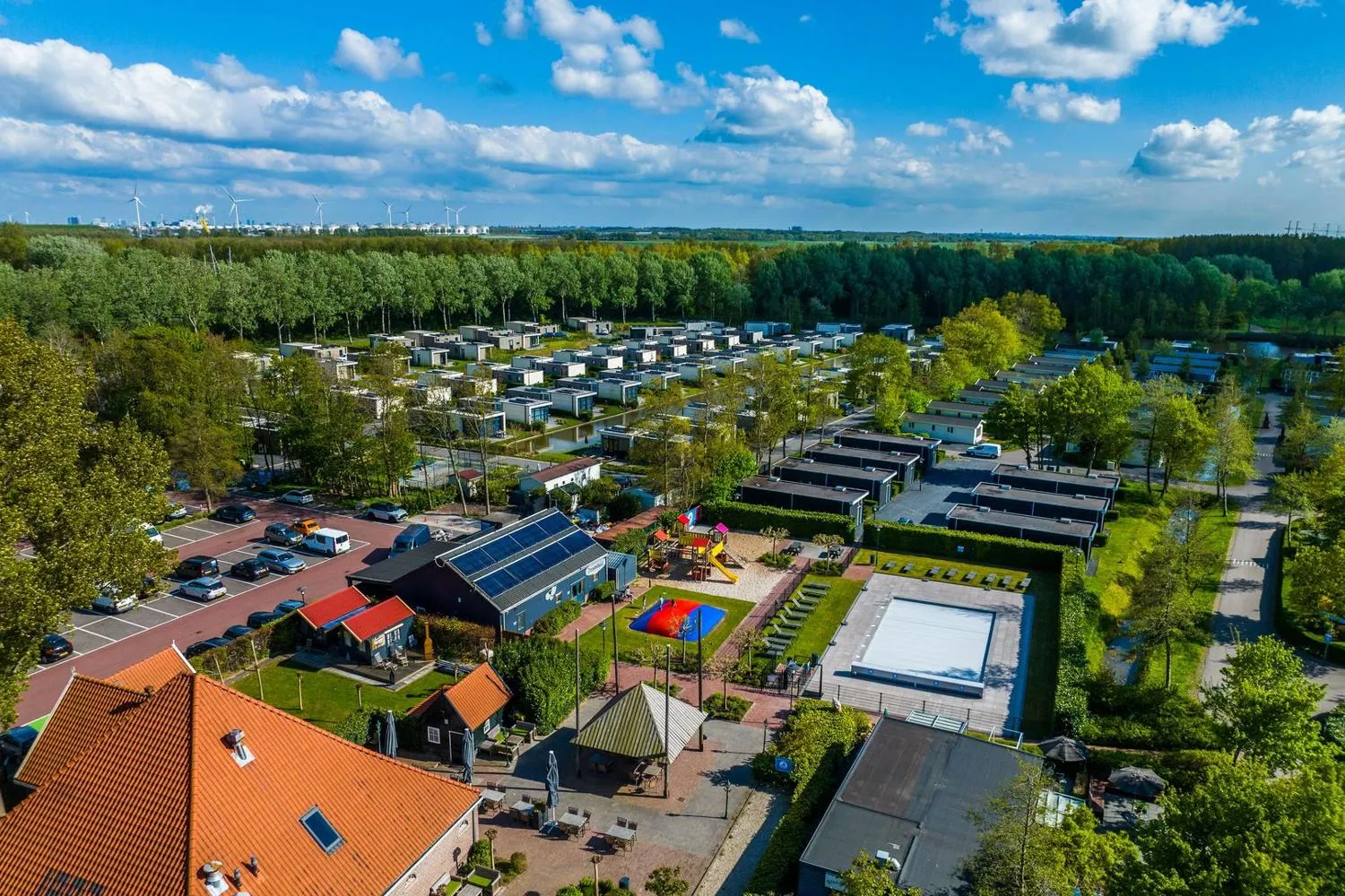 Ferienpark mit Hauptgebäude, Spielplatz, Schwimmbad und Chalets im Wald