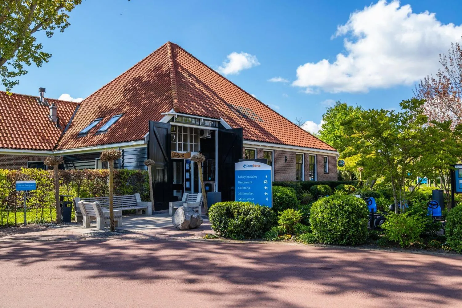 Hauptgebäude mit roten Dachziegeln und Parkschild zum Empfang